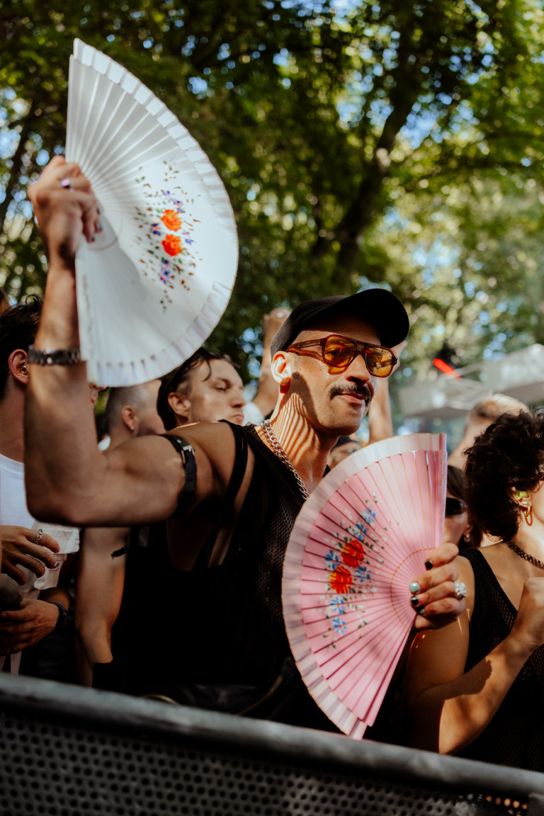Foto van persoon op een festival met twee waaier in zijn handen aan het dansen 