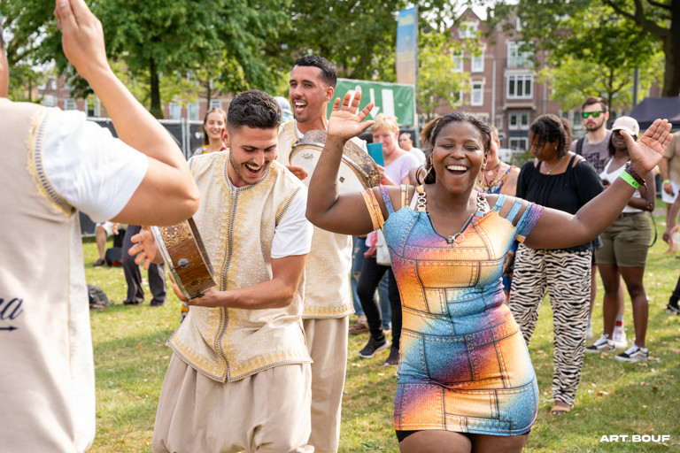Dame en een jongen die allebei aan het dansen zijn op muziek tijdens het African Food Festival. Ze kijken beide vrolijk. 